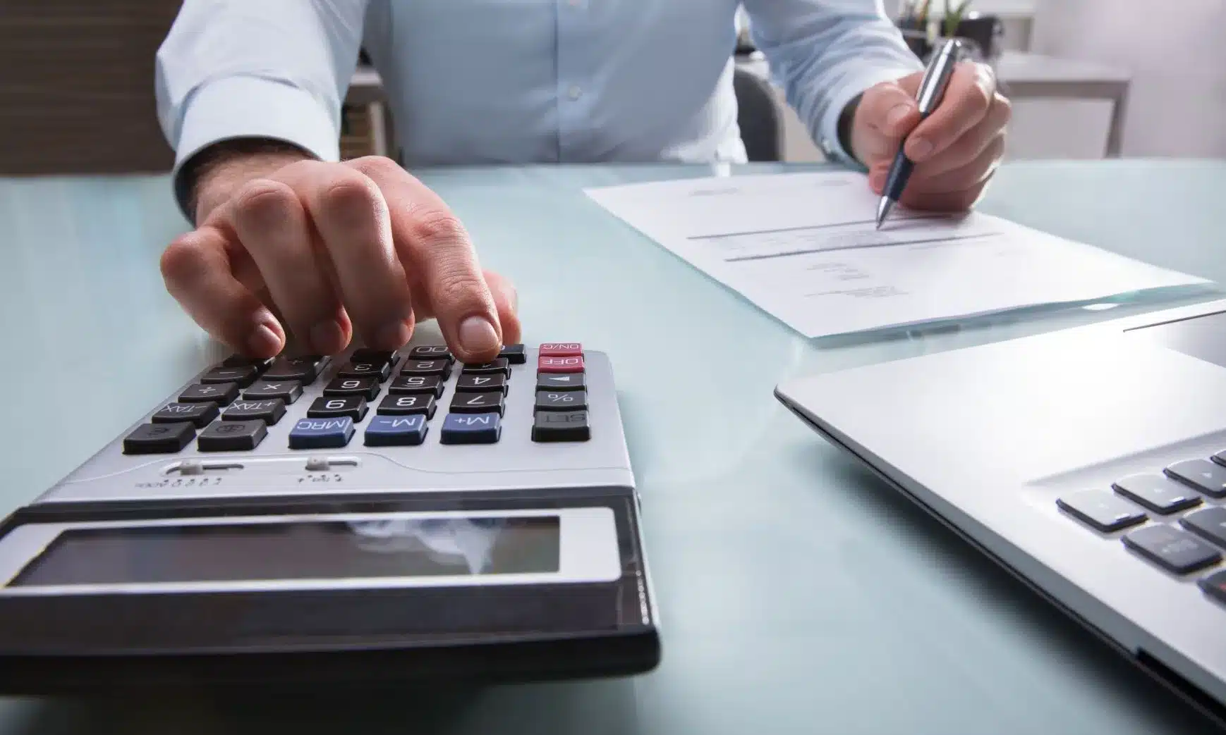 A tax professional entering data into a calculator in an office at daytime.