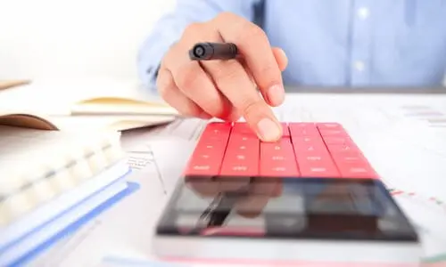 A closeup shot of a tax professional using a calculator while working on tax lien removal.