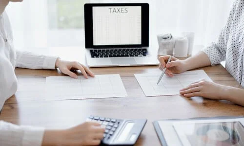 A tax professional at a desk with a client discussing their 1099 tax forms.