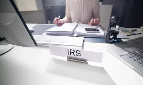 An IRS auditor at her desk calculating a taxpayer's taxes.