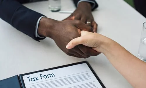 A closeup shot of an IRS agent and a taxpayer shaking hands after having reached an agreement to abate existing penalties.