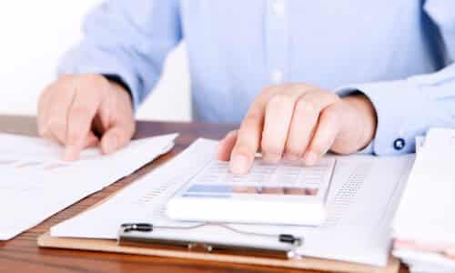 A tax expert at a desk, calculating self-employment taxes for a client.