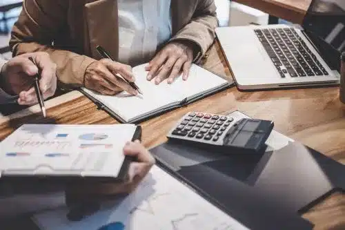 Closeup of hands taking notes in a notebook, tax lawyers calculate sums.