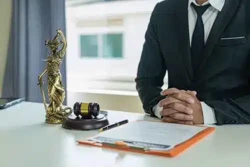 A tax lawyer sits at his desk with hands crossed.