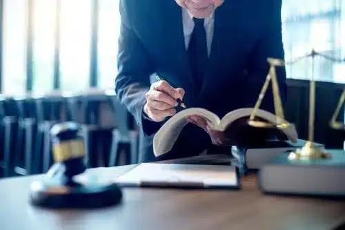 A tax lawyer bends over to study law out of a large book.