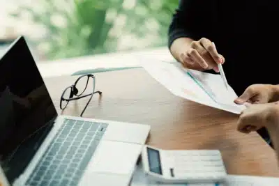 A tax expert at a desk with a client pointing out details on some documents.