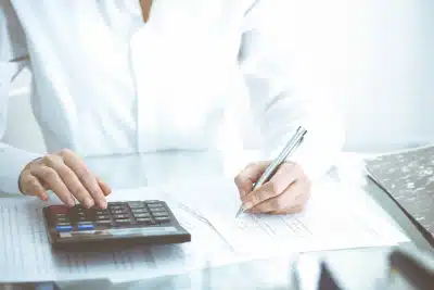 A tax professional with a pen and calculator working at a desk to respond to an IRS letter.