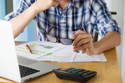 A taxpayer holding a pair of glasses in his hand while working on documents to release penalties.