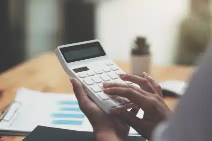 A person on a calculator computing penalties for missing deadlines on her taxes.