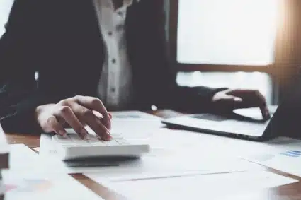 A business professional using a calculator and reviewing financial documents, focused on tax resolution strategies.