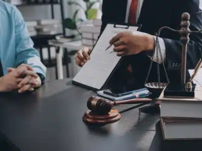 A Golden tax lawyer explaining the legal case of his client involving tax law challenges, with a scale of justice, gavel, and law books placed on the table.