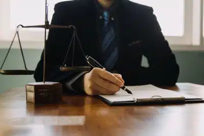 A tax relief lawyer serving Bozeman is sitting at an office desk while signing a document placed on a clipboard