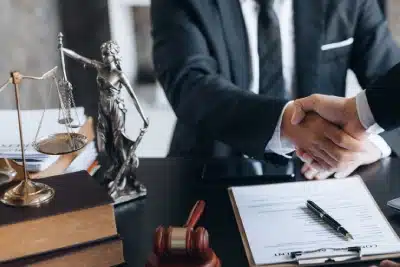 A business & payroll tax relief lawyer serving Bozeman is shaking hands with a colleague who stands on the opposite side of an office desk
