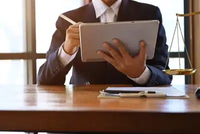 A Bozeman back tax filing lawyer works on a tablet while sitting in front of a window inside a law office