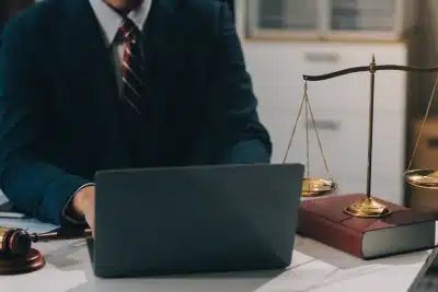 A Bozeman IRS penalty relief lawyer sits at their desk while working on a laptop as a balance scale and a hammer and gavel sit on both sides